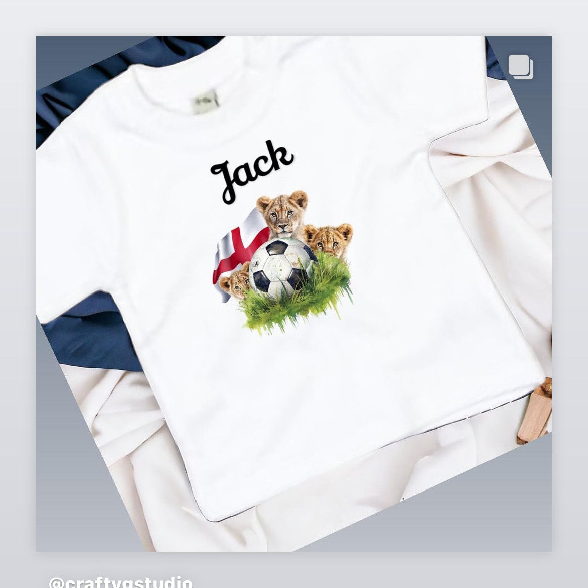 A white t-shirt with a graphic print of a lion and cubs playing soccer, and the name 'Jack' printed on the front.