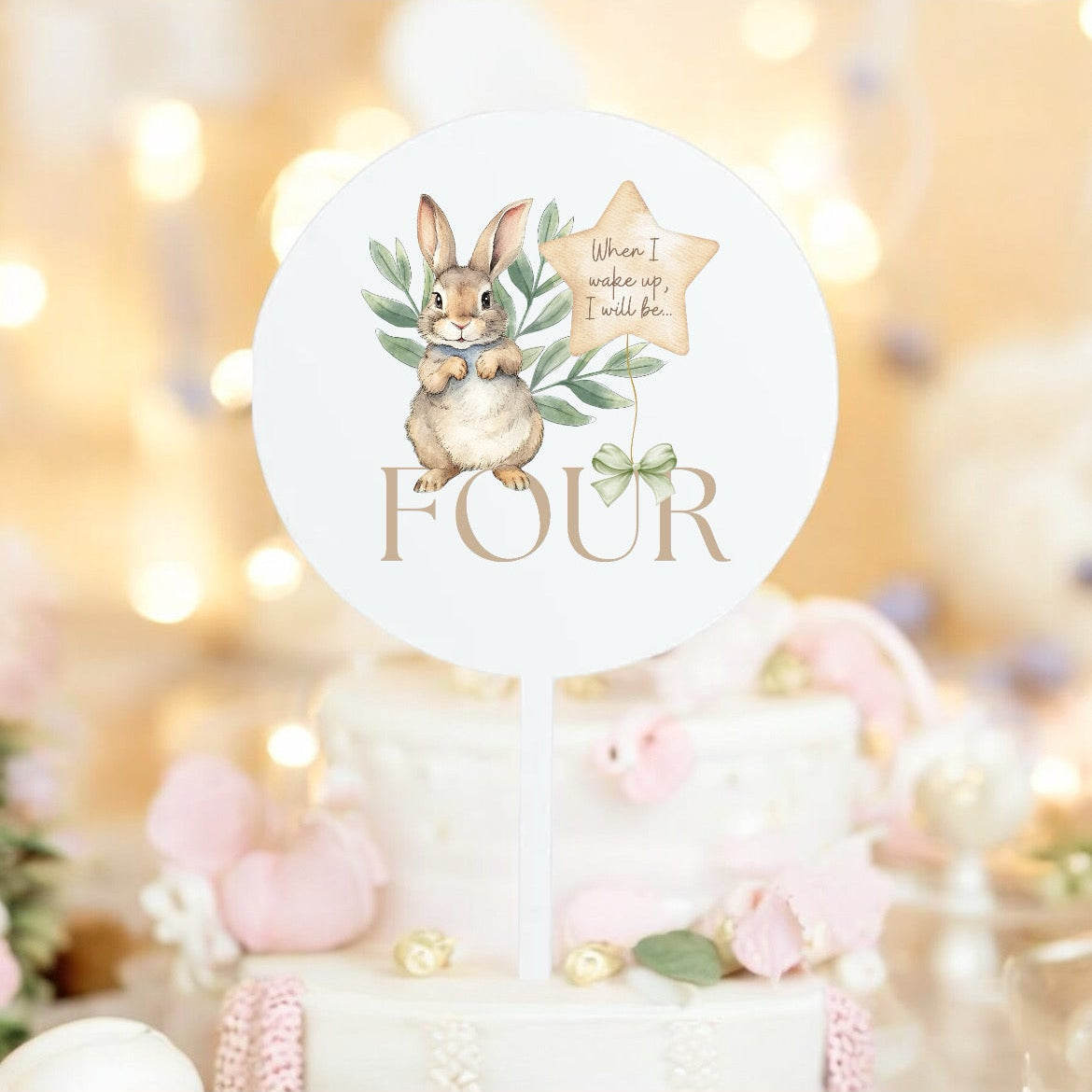 Decorative cake topper with bunny design and 'FOUR' text on a blurred festive background