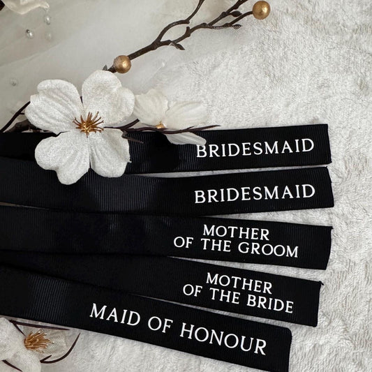 Black ribbons with white text on a light background with flowers