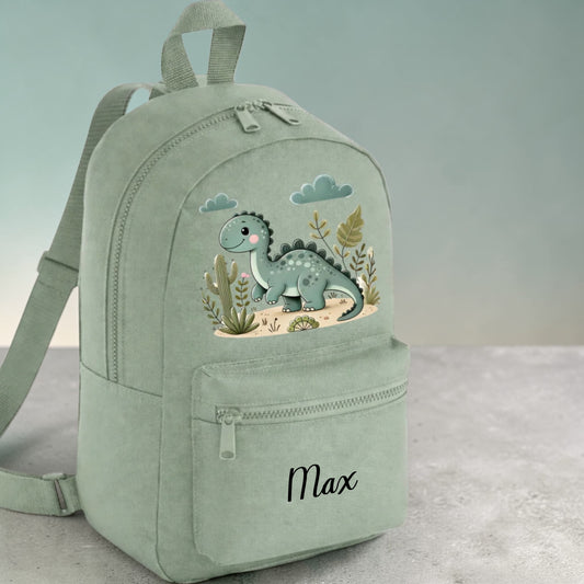 Green backpack with dinosaur design and 'Max' text on a light gray background