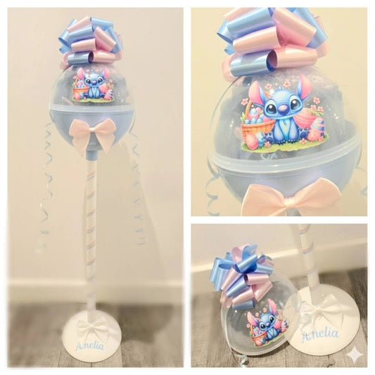 Decorative item with cartoon character inside a clear dome, surrounded by colorful bows.