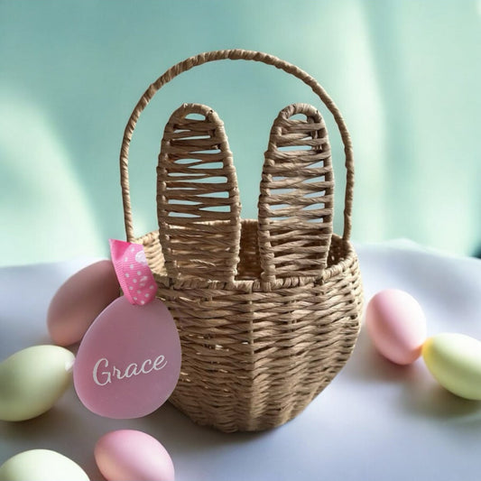 Wicker basket with bunny ears and 'Grace' tag on a light green background