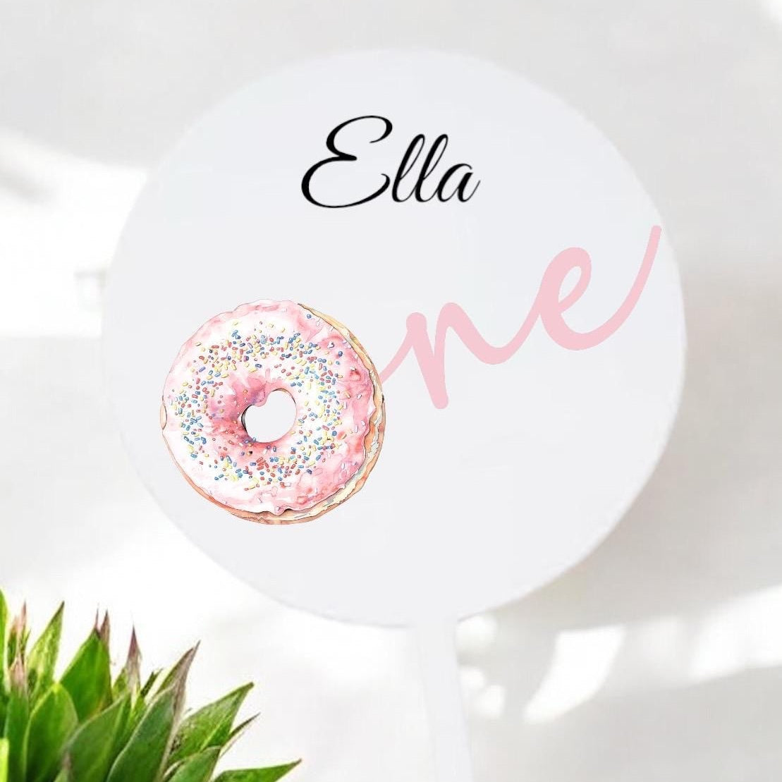 Round white sign with 'Ella One' text and a decorative donut design on a light background.