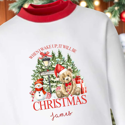 White sweatshirt with red collar featuring Christmas-themed design with teddy bear, snowman, and text.