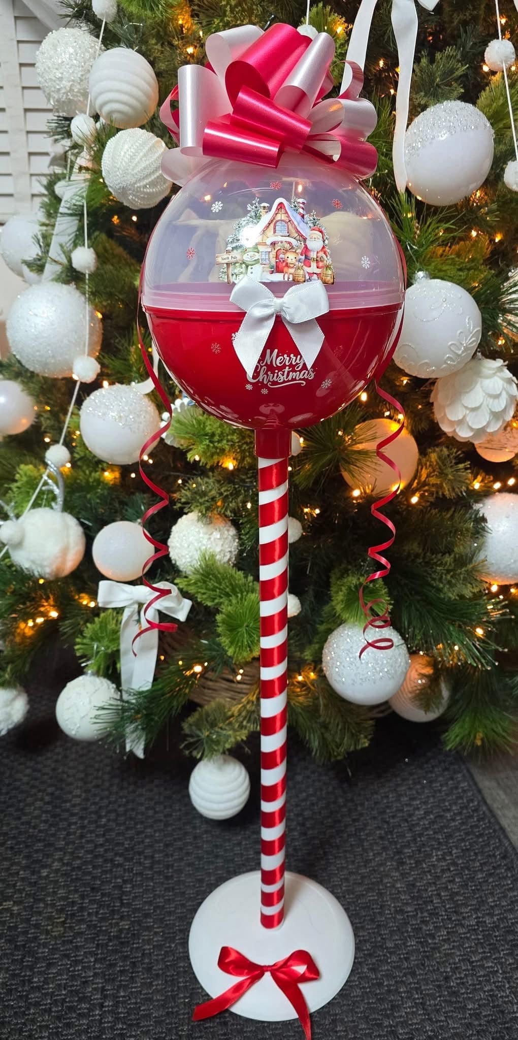 Decorative Christmas candy cane with a bubblegum ball and Santa Claus design, against a festive tree background.